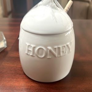 A classic porcelain honey holder with wooden honey dipper.